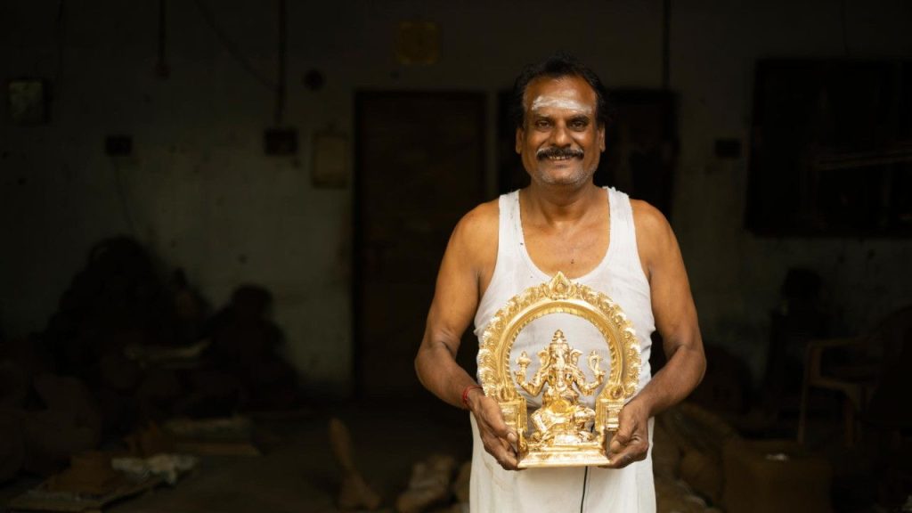 An artisan holding a swamimalai bronze idol