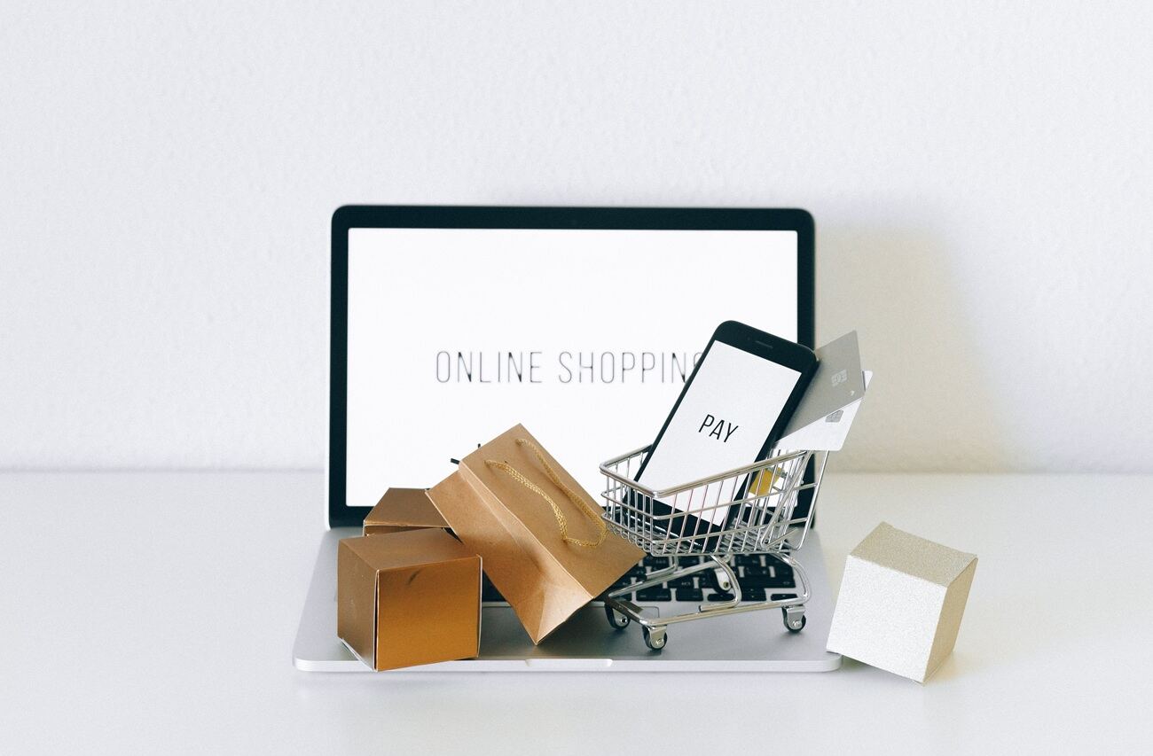 A tablet with the phrase 'online shopping' on it, a tiny shopping cart, and shopping bags